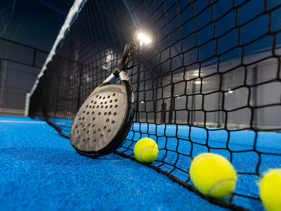 ballen bij het net van een blauwe padeltennisbaan