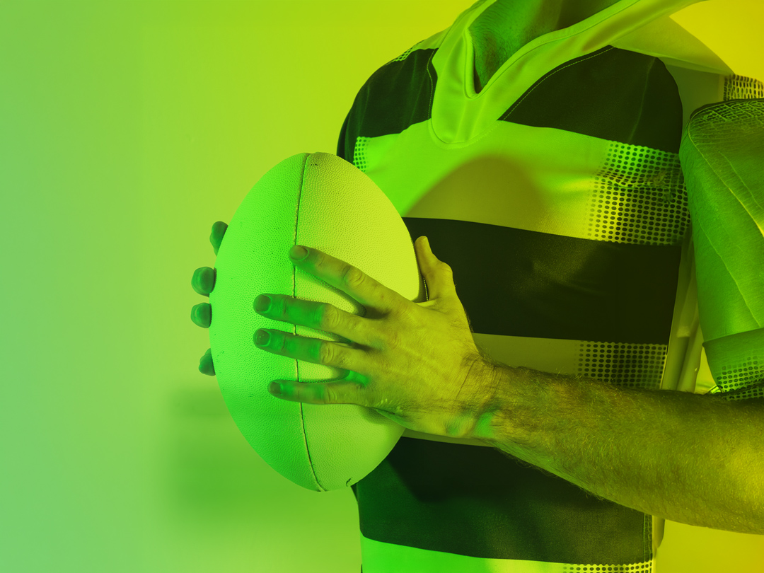 Man met rugbybal in zijn handen, gezicht afgesneden, groene tint kleuren